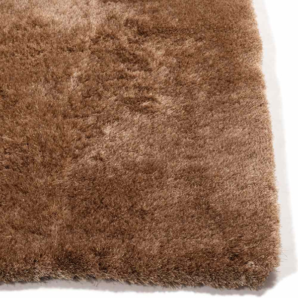 Hochflor-Teppich in brauner Farbe liegt auf einem Boden. Der Teppich zeigt eine weiche, flauschige Textur und hebt sich deutlich vom Untergrund ab. Er ist in einem eleganten Design konzipiert.