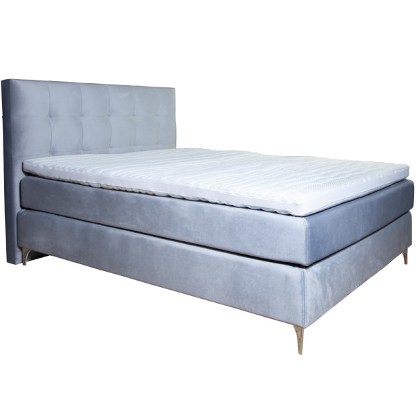 Boxspringbett mit grauem Stoffbezug steht auf einem Boden. Die Matratze hat einen Topper und ist in einer geschlossenen Position. Das Bett hat ein gepolstertes Kopfteil mit quadratischer Steppung.