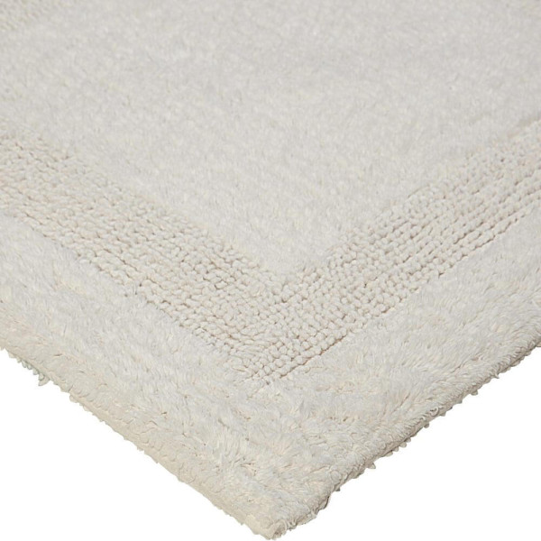 Hellgrauer Badteppich mit weichgebürsteter Oberfläche und quadratischem Muster. Der Teppich ist aus Baumwolle gefertigt und eignet sich ideal für Badezimmer.