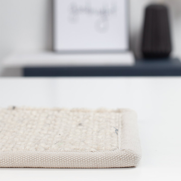 Hellbeige Teppich nach Maß mit feiner Struktur steht bereit. Er zeigt eine Baumwoll-Einfassung und eignet sich ideal für verschiedene Wohnräume. Qualität und Anpassungsmöglichkeiten sind betont.