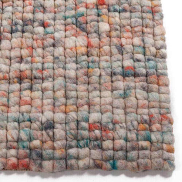 Bunte Teppichoberfläche aus Schurwolle mit einer sanften, strukturierten Optik. Die Farben reichen von Beige über Grau bis zu verschiedenen bunten Tupfern, was den Teppich vielseitig gestaltet.