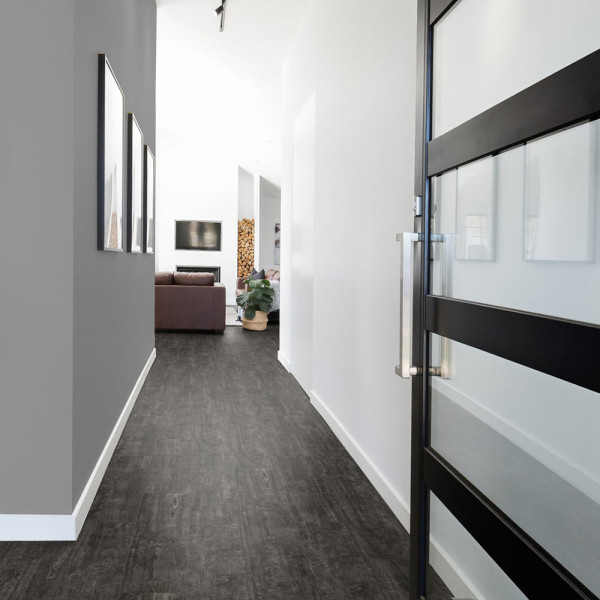 Dunkler Vinylboden mit einer Struktur, die an verwittertes Holz erinnert. Die Oberfläche weist verschiedene Holzmaserungen und -nuancen auf. Dieser Bodenbelag eignet sich für stilvolle Innenräume.