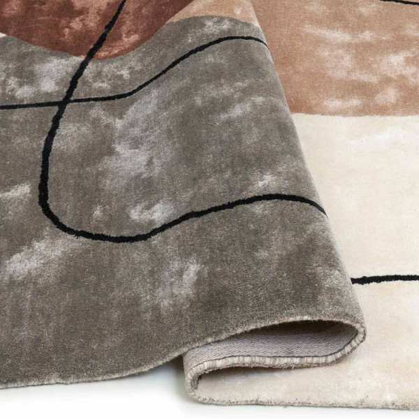Multicolor Teppich mit grafischem Design. Er zeigt verschiedene geometrische Formen in Grau, Braun und Beige. Die Farben und Strukturen verleihen dem Teppich einen modernen Look.
