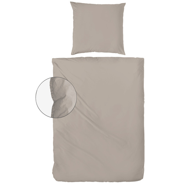 Flanell-Bettwäsche in sanfter, beiger Farbe liegt drapiert auf einem Bett. Ein Kissenbezug und die Bettdecke sind sichtbar, zusammen mit einem Detailansicht-Ausschnitt der Naht.
