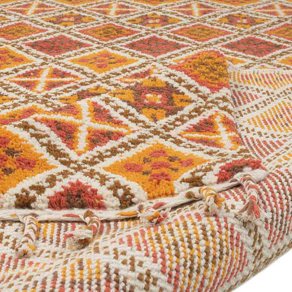 Terracottafarbener Teppich mit geometrischem Muster in gelb, rot und grün. Der Teppich hat Fransen an der Oberkante und misst 170 x 240 cm.