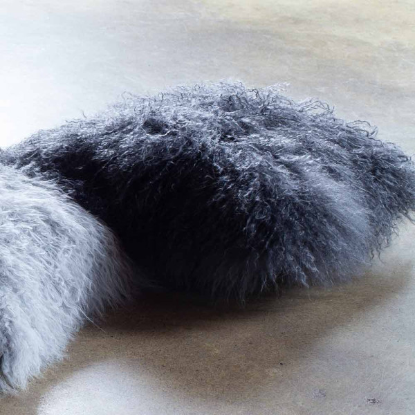 Flauschige, dunkelgraue Kissenhülle aus Lammfell mit unregelmäßiger Oberfläche. Die Kissenhülle hat eine quadratische Form und vermittelt einen gemütlichen Eindruck. Sie eignet sich für verschiedene Einrichtungsstile.