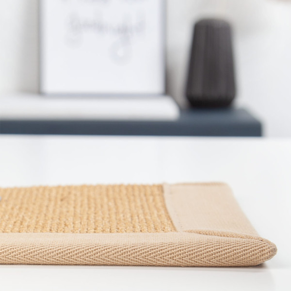 Sisal-Teppich in einer natürlichen, strohgelben Farbe zeigt eine strukturierte Oberfläche und eine beige Kante. Der Teppich eignet sich für maßgeschneiderte Designs.