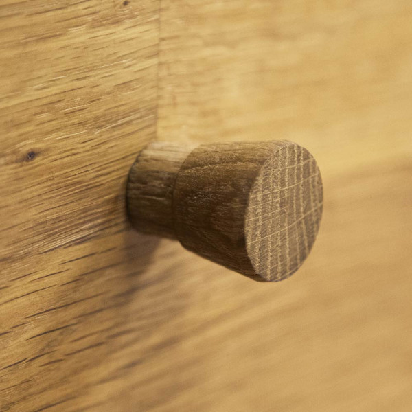 Rustikaler Nachttisch aus Holz steht neben einem Bett. Darauf befindet sich eine weiße Büste, während ein Topf mit einer Pflanze im Hintergrund steht. Die Wand ist dunkel gestrichen.