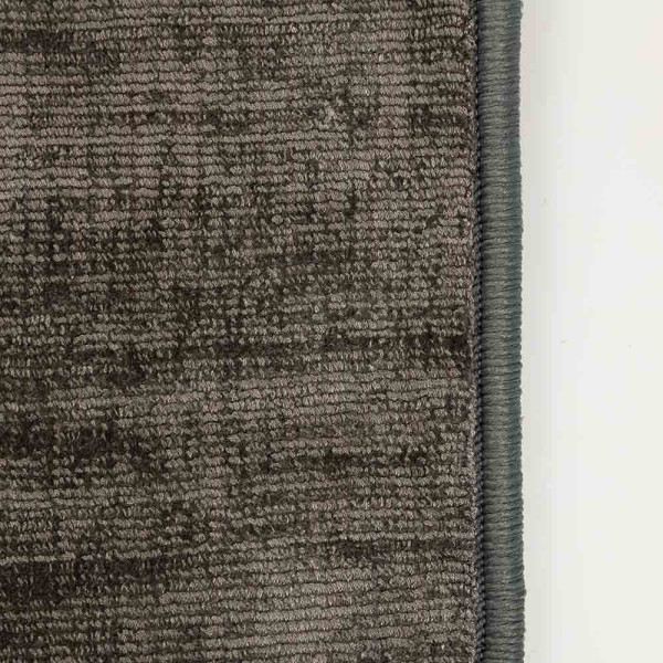 Dunkler, kurzfloriger Teppich im Crushed Velvet-Stil mit einer unregelmäßigen Struktur. Der Teppich steht im Fokus der Präsentation als modisches Einrichtungselement.